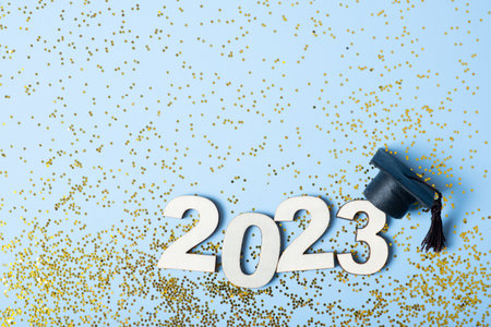 Class of 2023 concept. Wooden number 2023 with graduated cap on colored background