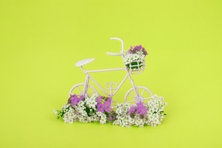 Decorative bicycle with flowers on yellow background. Spring minimalistic concept.の写真素材