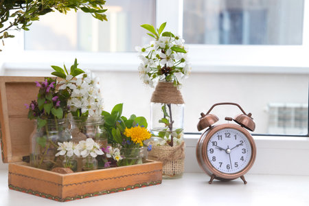 Alarm clock with flowering branches in a wooden box on the windowsill. spring forward.の写真素材