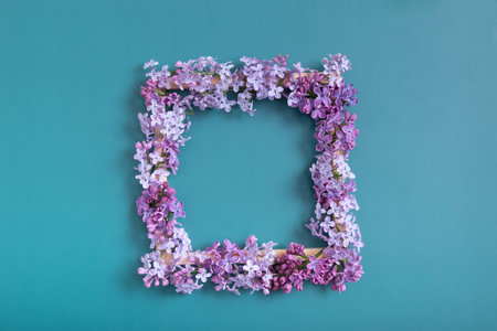 Summer or spring composition on a turquoise background. Lilac flowers square with copy space top view. Summer, spring floral concept.の写真素材