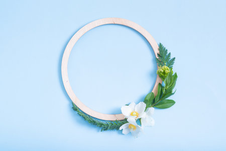 Summer or spring composition on a blue background. Wooden frame and anemone flowers and leaves with...