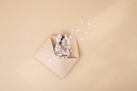 Kraft envelope with a spring twig and white spring flowers on a beige background.