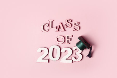 Class of 2023 concept. Wooden number 2023 with graduated cap on colored background