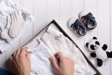 Female hands put children's clothes, shoes and toys into a box. Second hand clothing recycling concept.の写真素材