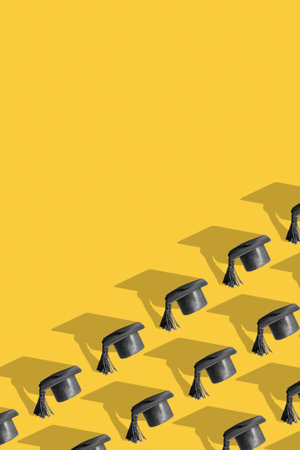 Pattern with black graduated cap on yellow background with copy space. education vertical background.の写真素材