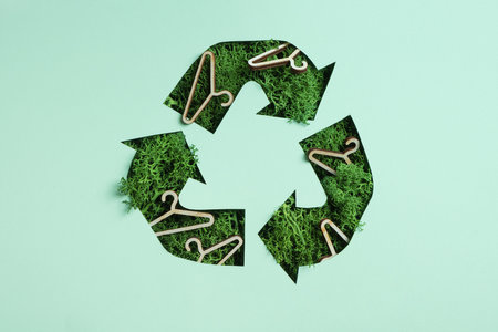 Green moss and coat hangers under paper cut recycling symbol. Save planet recycling cloth concept.の写真素材