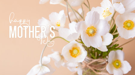 Happy Mothers Day greeting card with close up white anemones flowers on colored background.