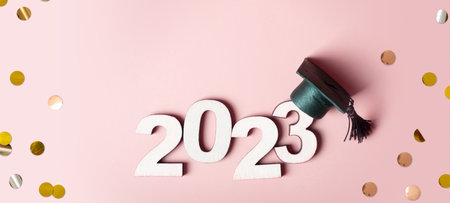 Class of 2023 concept. Wooden number 2023 with graduated cap on colored background.