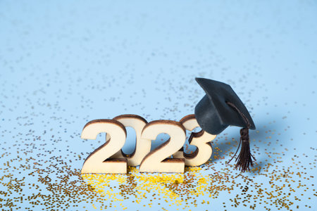 Class of 2023 concept. Wooden number 2023 with graduated cap on colored background.
