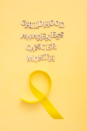 Childhood cancer awareness month text with ribbon on yellow background. vertical format.の写真素材