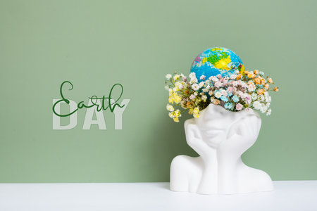 Earth day text with head-shape vase with flowers and world globe.の写真素材
