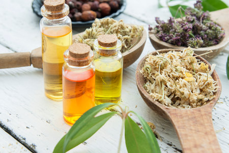 Dry herbs in a wooden spoons with essences in glass bottles. alternative medicine concept.の写真素材