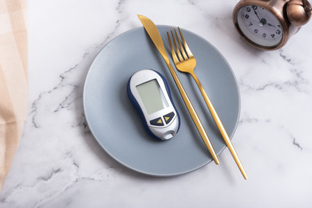 Plate with glucometer and cutlery on plate and alarm clock. Diabetes diet concept.