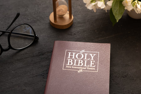 Top view of the Holy Bible on the desktop with hourglass. The concept of Bible study time.
