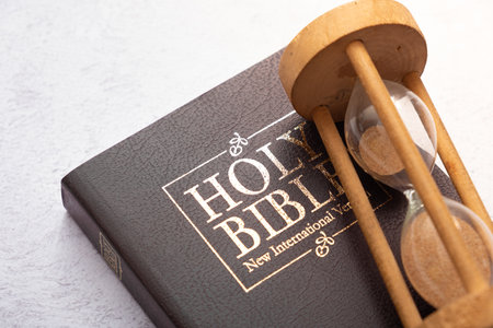 Top view of the Holy Bible on the desktop with hourglass. The concept of Bible study time.