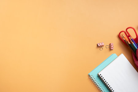 Notebooks and stationary on colored background. copyspace. Kids work space top view, flat lay....