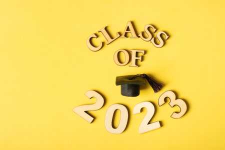 class 2023 concept. Wooden number 2023 with graduated cap on yellow background.