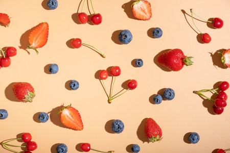 Pattern with strawberries, cherries and raspberries on an orange background.の写真素材