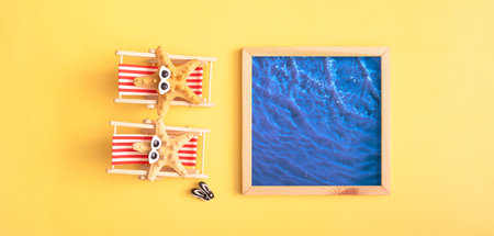 Two folding beach chairs with starfish in glasses and a pool on a yellow background. The atmosphere of summer recreation by the pool. Minimalist abstraction.の写真素材