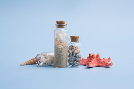 Minimalistic summer idea with mini bottles, small, shells, sand, sea star. The creative still life...