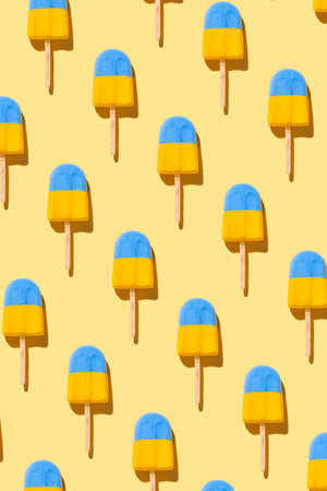 Trendy sunlight summer pattern made with blue-yellow ice cream on bright light yellow background. Minimal summer concept. vertical photo.の写真素材
