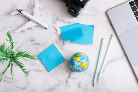 Travel flat lay composition with laptop, camera, airplane, globe and note paper. Buy online ticket...