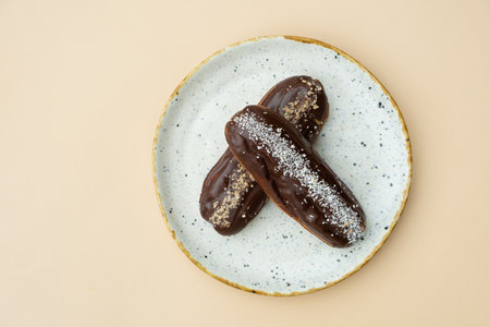 Eclairs in round plate flat lay composition on beige background.の写真素材