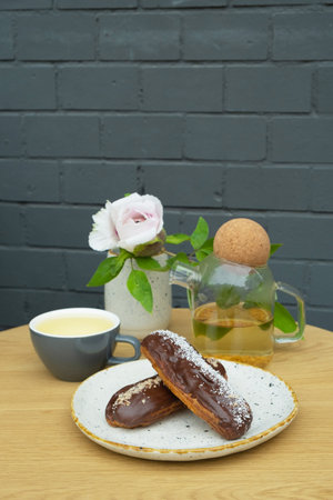 Eclairs with tea on a table in a cafe. Sweet food still life.