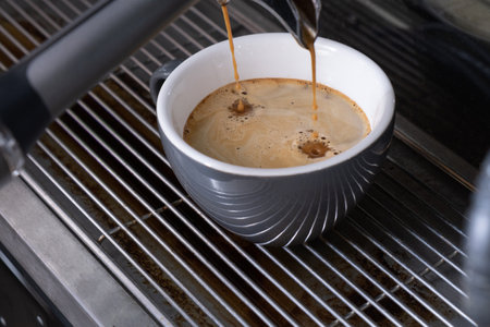 Preparing espresso on professional coffee machine in coffee shop or cafe close up. Pouring strong coffee in gray cup.の写真素材