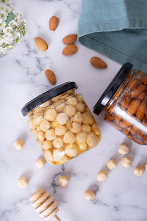 Glass jars with honey and nuts. Almonds and hazelnuts in honey top view, flat lay.の写真素材