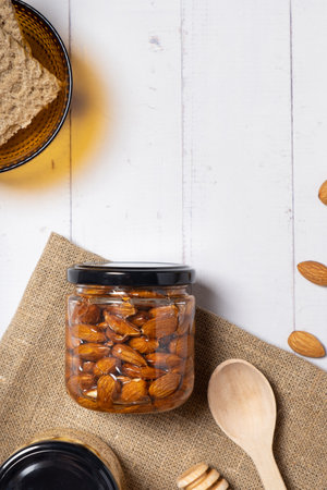 Glass jar with honey and nuts on beige background. Almond in honey. top view.の写真素材