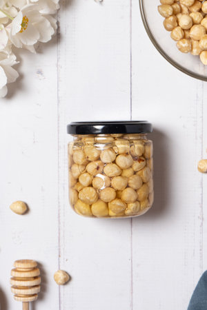 Glass jar with hazelnuts honey and nuts on beige background flat lay. Hazelnuts in honey. top view.の写真素材