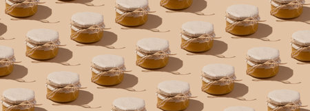 Pattern from glass jar with honey under kraft paper on a string on beige background. Sweet food monochrome bannerの写真素材