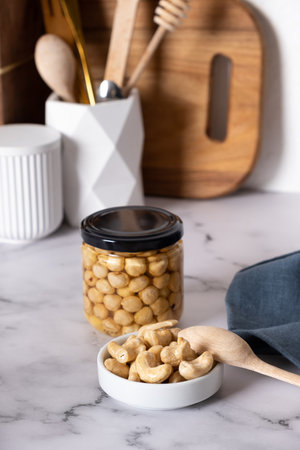 Ð¡ashew in honey with spoon with glass jars on marble backgroundの写真素材