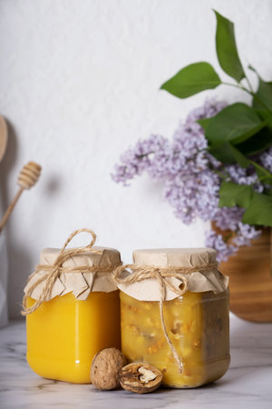 Jars with honey and walnuts. Walnuts in honey in the kitchen interior.の写真素材