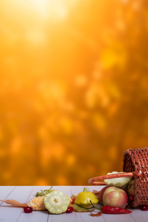 Autumn composition with a basket of apples, squash, peppers on the background of an autumn bokeh. Autumn harvest concept.の写真素材