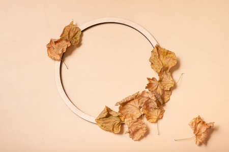 Autumn composition. Wreath made of dried leaves and wooden ring on pastel beige background. Autumn,...