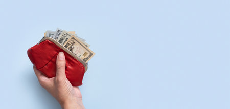 Wallet with dollars in female hand on blue background with copy space. Minimalistic financial concept banner format.の写真素材