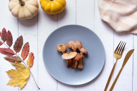 Pumpkins and mushrooms on a plate with cutlery on wooden background flat lay, top view.の写真素材