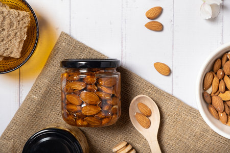 Glass jar with honey and nuts on beige background. Almond in honey. Top view.の写真素材