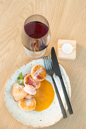 A glass of wine with cheesecakes on plate on a wooden table flat lay, top view.の写真素材