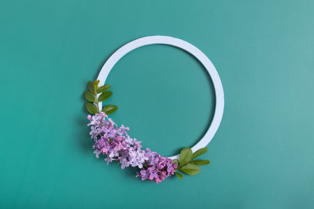Summer or spring composition on a green background. Lilac flowers with round wooden frame copy space top view. Summer, spring floral concept.の写真素材