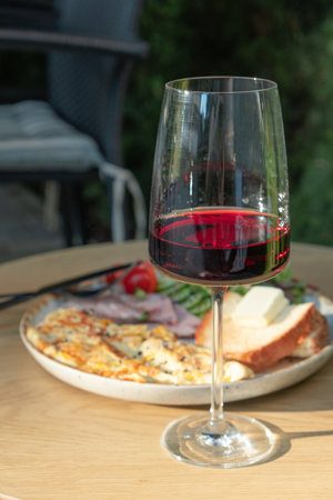 A glass of wine and plate with omelette, turkey and vegetables.の写真素材
