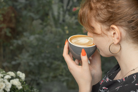 Woman hold cup of coffee and drink latte in cafeの写真素材