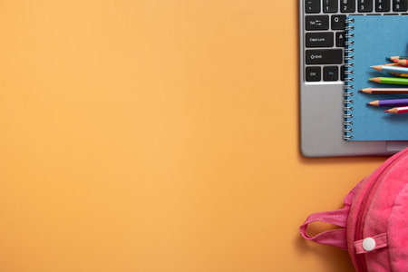 Colorful pencils and note on laptop with backpack on colored background. copyspace. Top view, flat lay.の写真素材