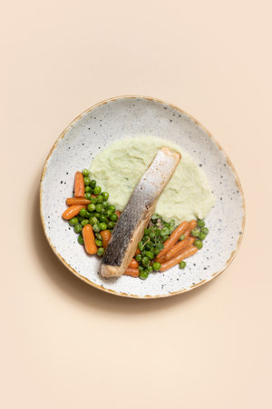 Salmon fillet on cauliflower puree with peas and carrots top view.の写真素材
