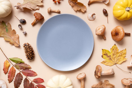 Empty plate with pumkins, mushrooms and autumn leaves on beige background top view. Monochrome autumn flat lay.の写真素材