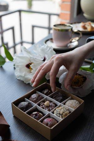Chocolate craft candy in female hand and candy box.の写真素材