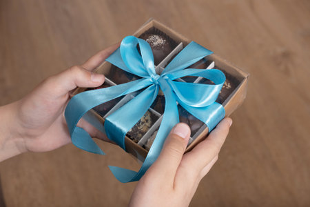 Gift box with chocolate craft candies in boys hands. Sweet gift box.の写真素材