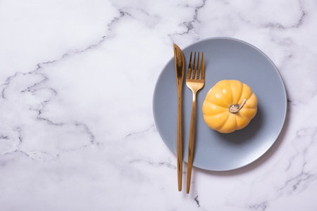 Orange pumpkin on a blue plate with cutlery. Minimalist concept of the autumn menu.の写真素材